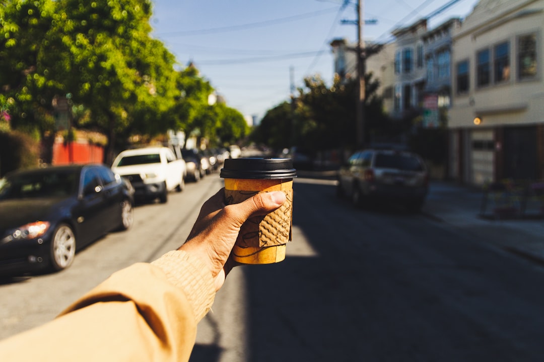 person-holding-brown-and-black-disposable-cup-on-road-tcan7nogq30