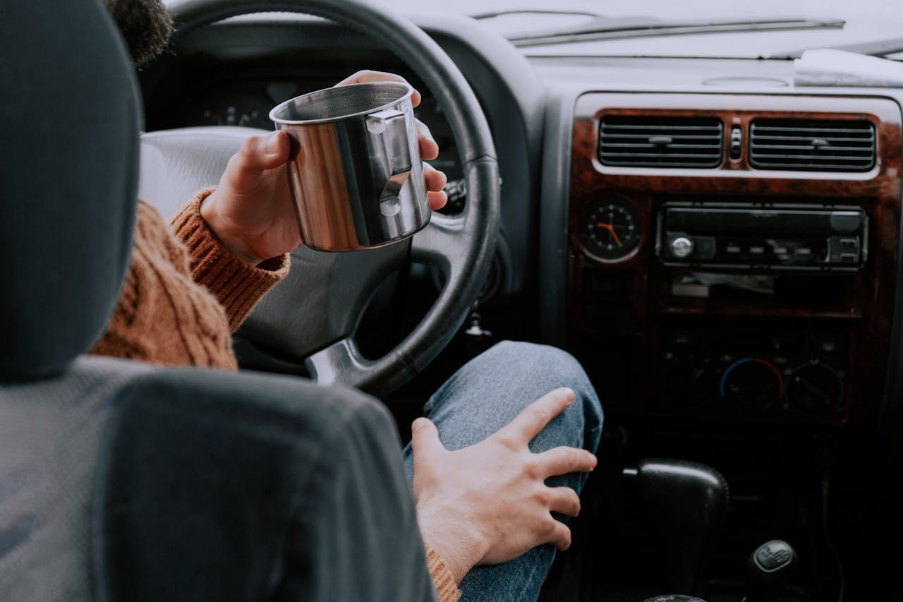 about-us Man holding a stainless steel mug inside a car, emphasizing comfort and warmth on the go.